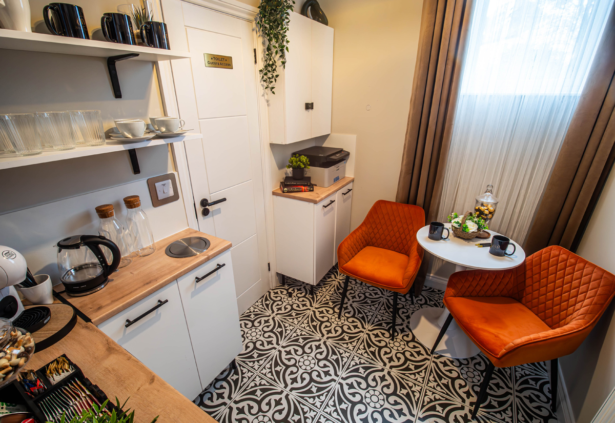 Przytulny aneks kuchenny z pomarańczowymi krzesłami.