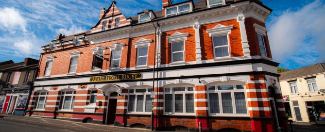 Apart Hotel Rugby's historische rode bakstenen gevel onder een blauwe hemel, biedt accommodatie in Rugby.