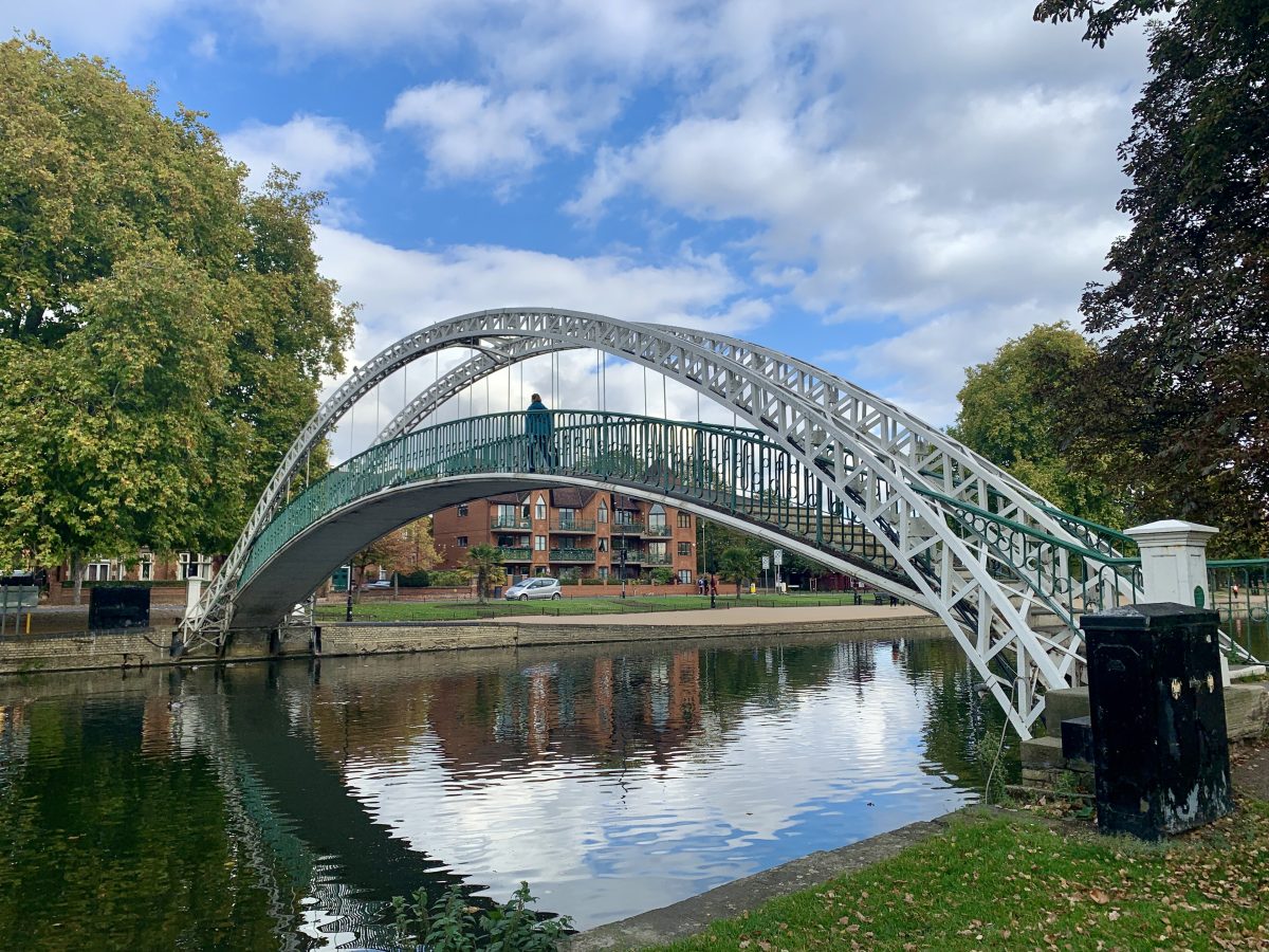 The white arched suspension footbridge over the River Great Ouse in Bedford, reflected in the water