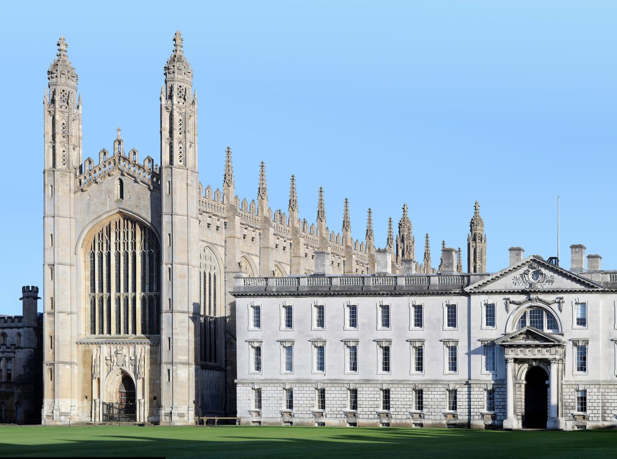 King's College Chapel with its tall pinnacles beside the pale stone Gibbs Building across a lawn in Cambridge
