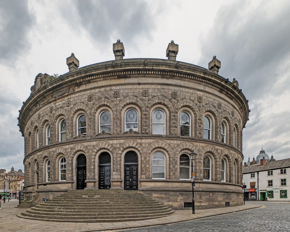 The oval stone Corn Exchange in Leeds with its curved steps, under grey clouds