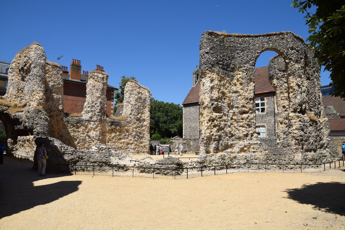 The flint walls and arched window of the Reading Abbey ruins under a deep blue sky