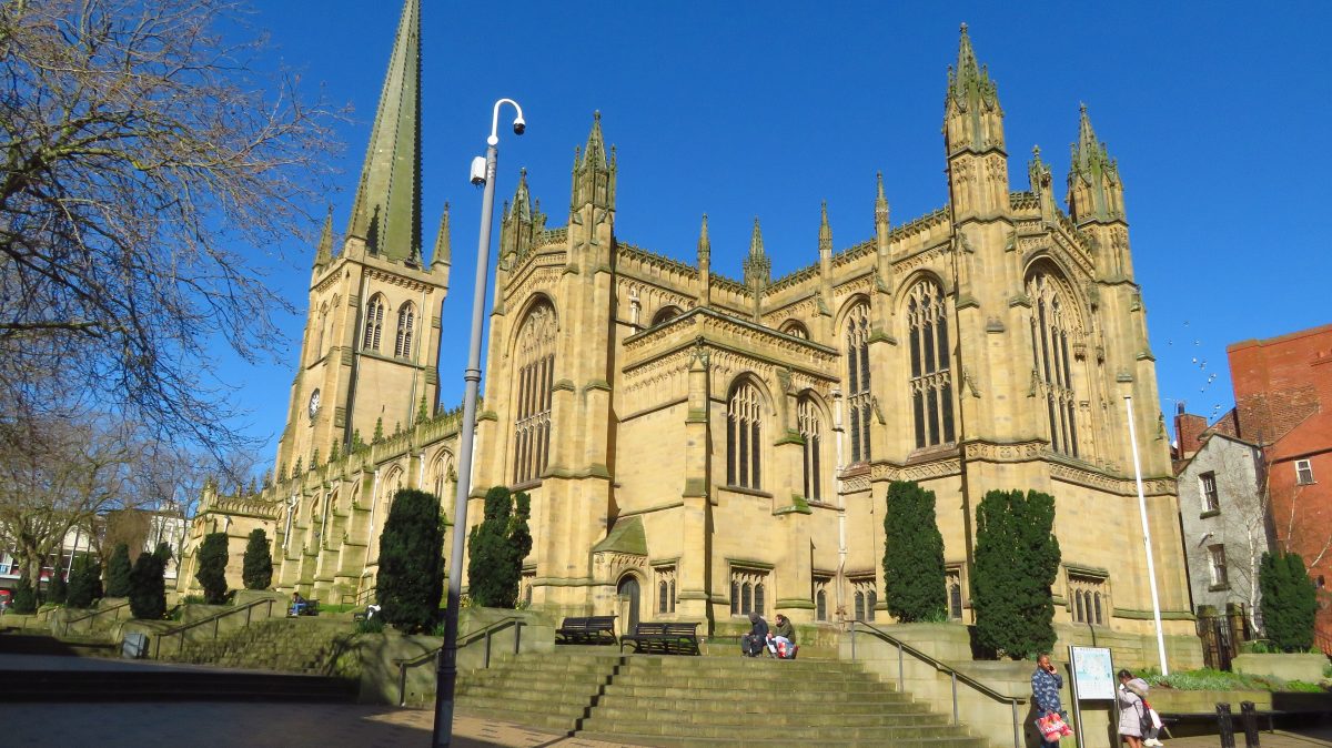 Wakefield Cathedral with its tall spire, in golden sandstone against a deep blue sky